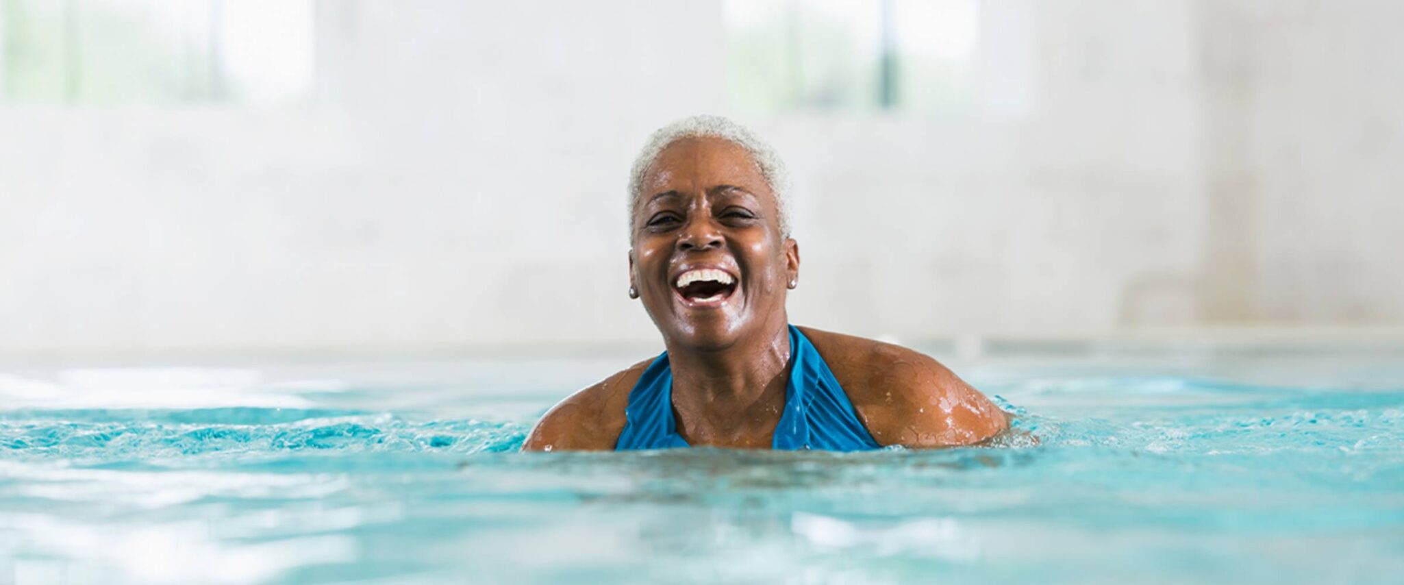 A senior woman smiles while swimming in a salt water pool