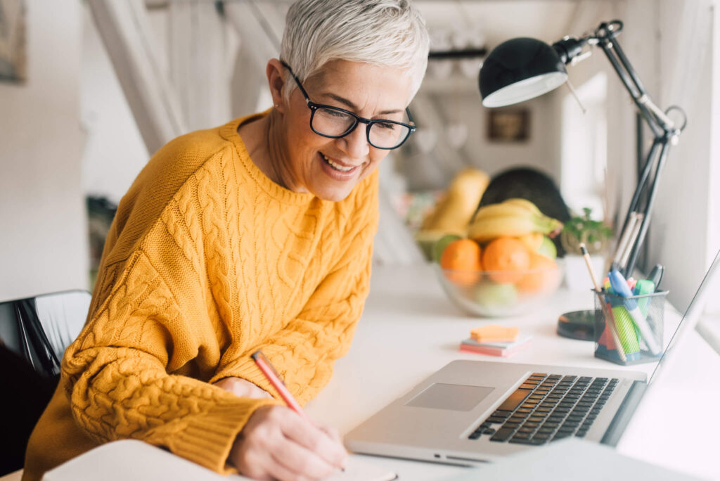 Woman writing next to her laptop