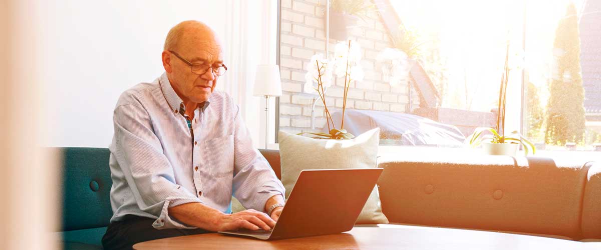 A senior man looks at his laptop