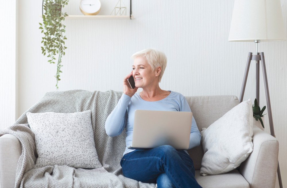 Modern happy old lady sitting on sofa at home