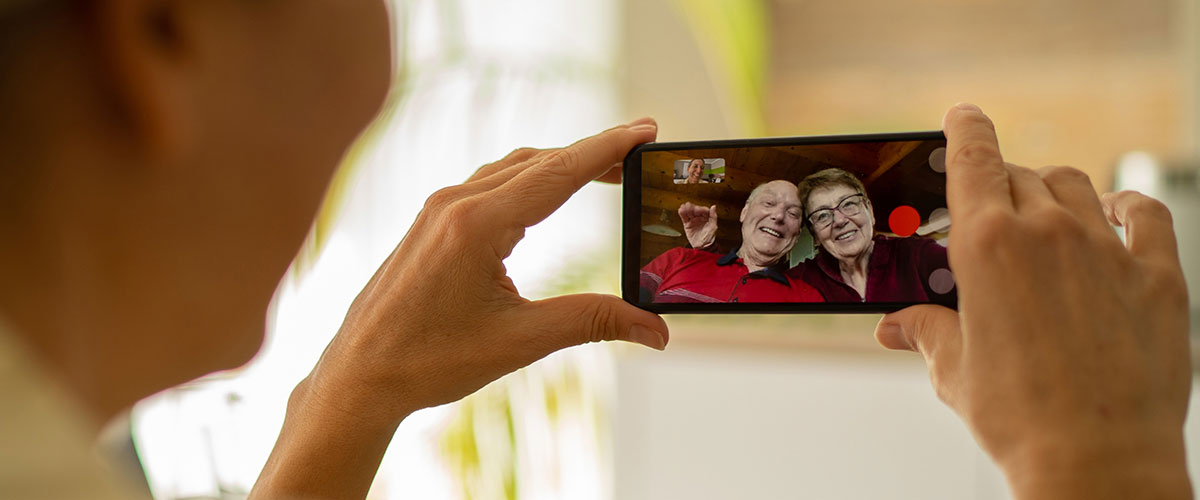 Senior woman uses her cell phone to video call with relatives to avoid senior isolation.