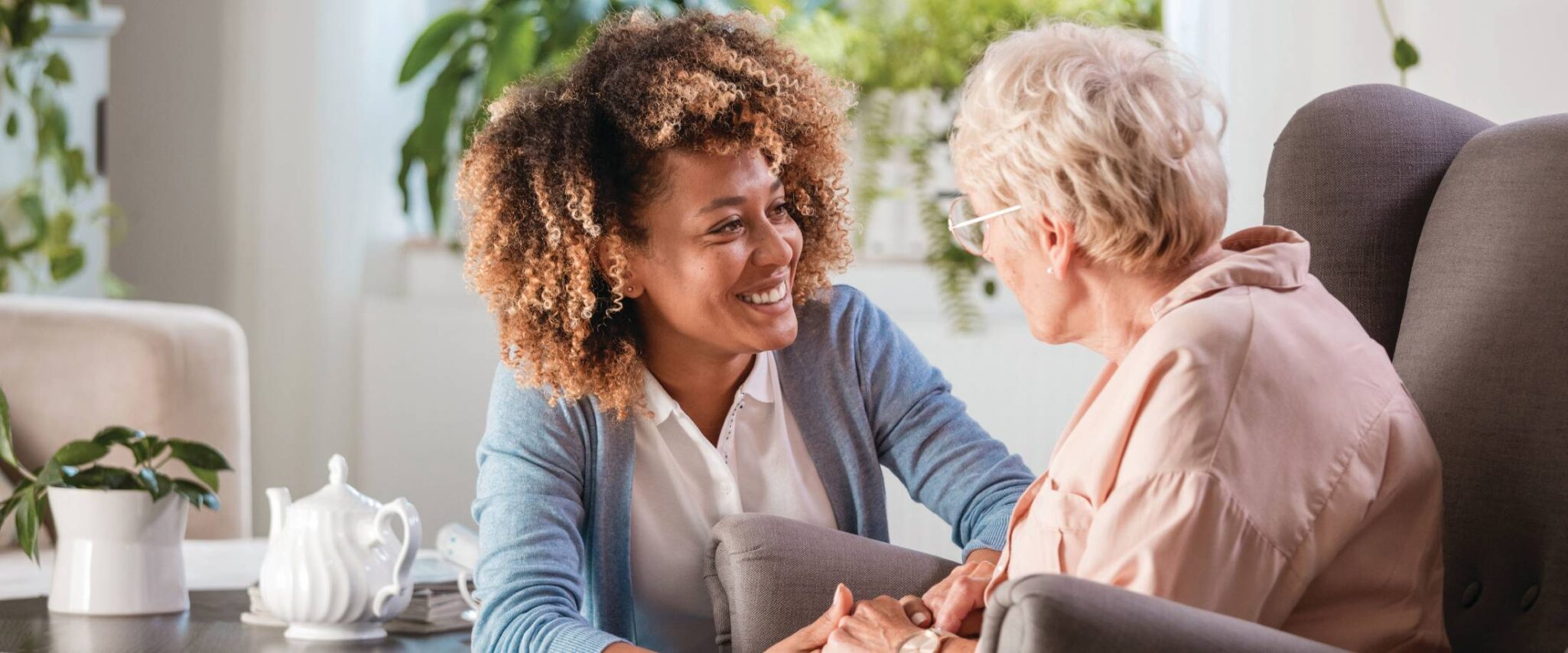 elderly woman sitting down in a chair with a caregiver