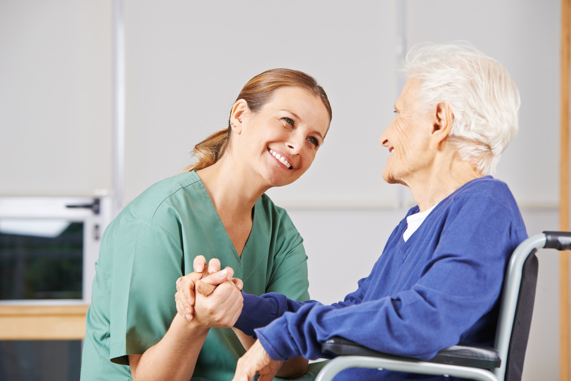 Happy senior woman holding hands with her caregiver