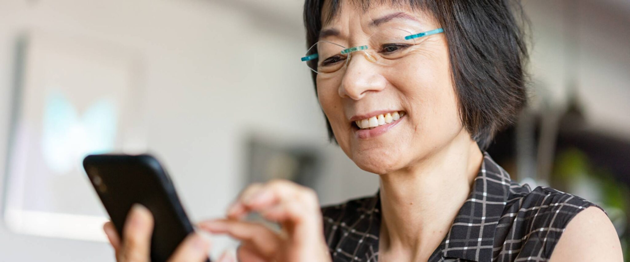 senior woman looks and smiles at her smart phone