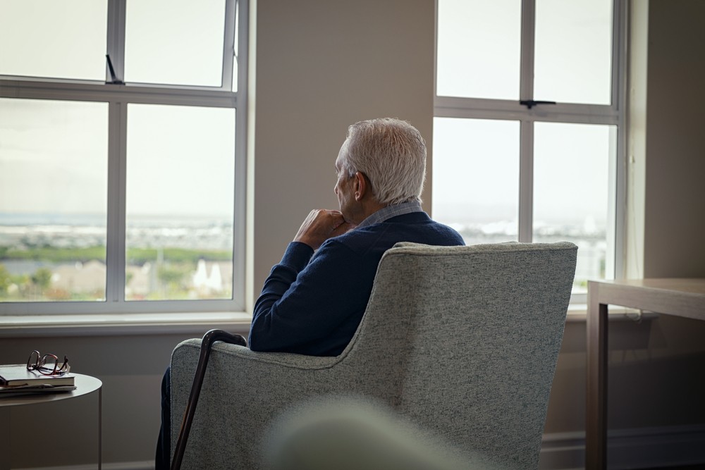 Senior man sitting at home looking out the window