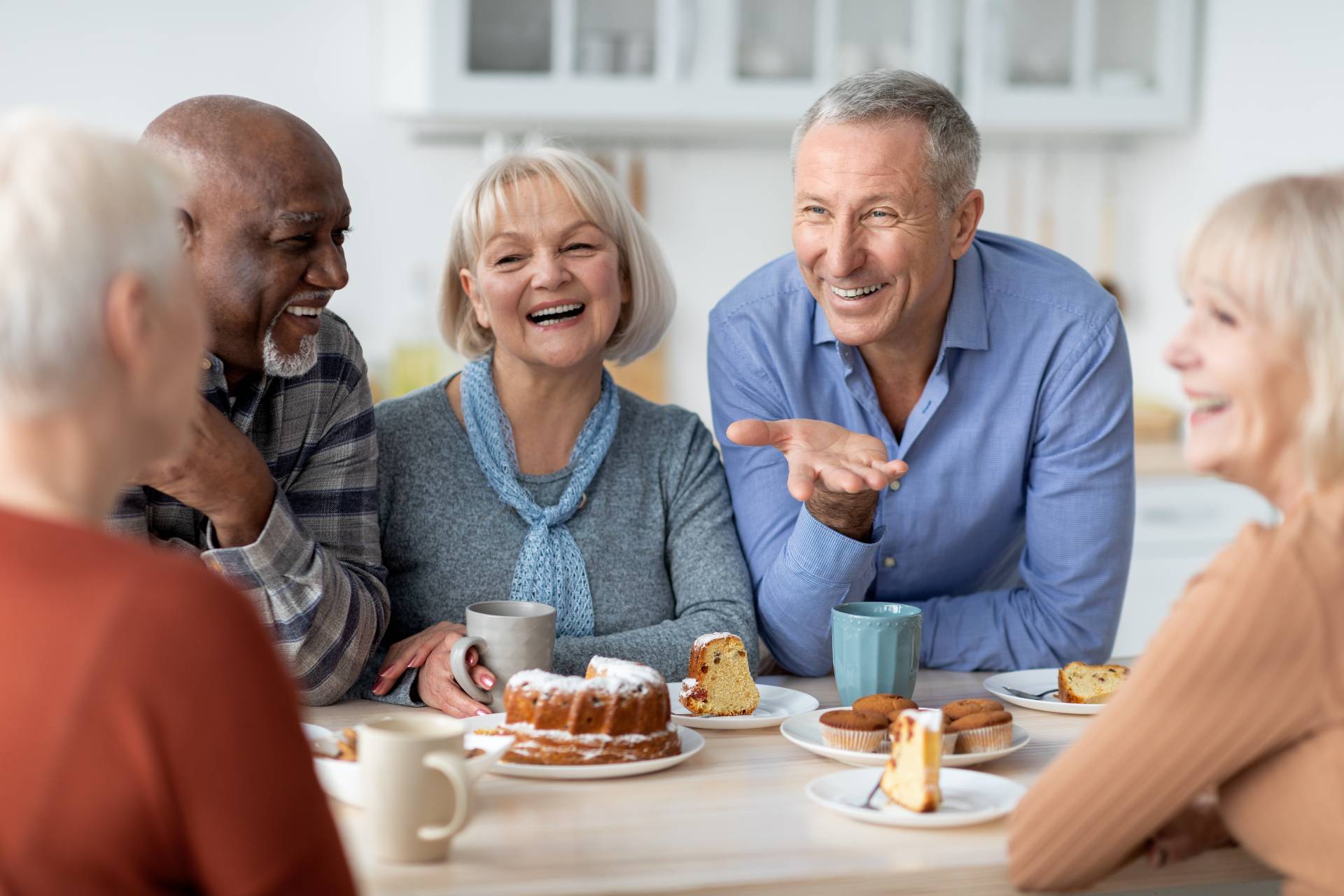 Diverse group of happy senior friends talking and having lunch together