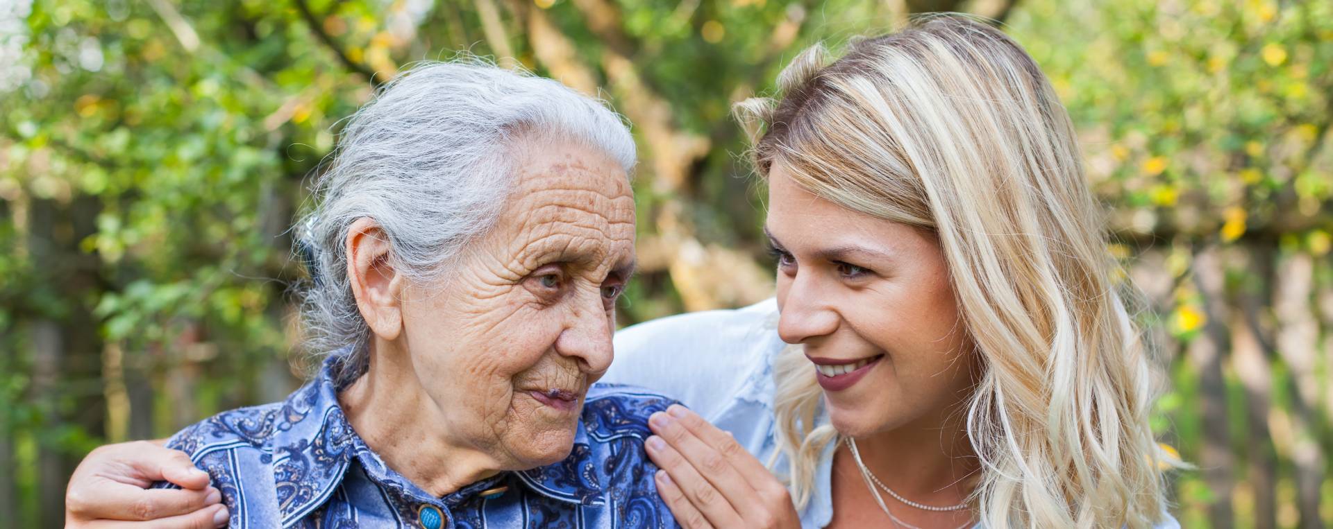 senior talking with a healthcare worker outside a memory care community