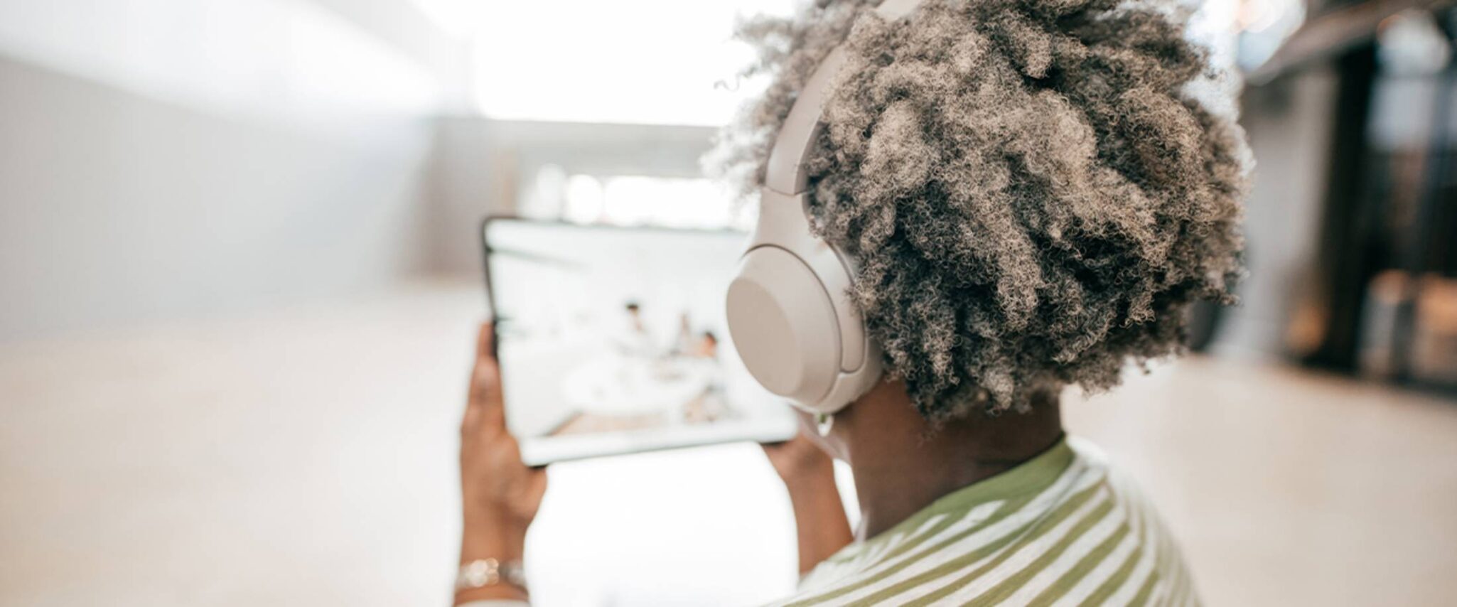 senior woman looking at a smart tablet with over the ear headphones on