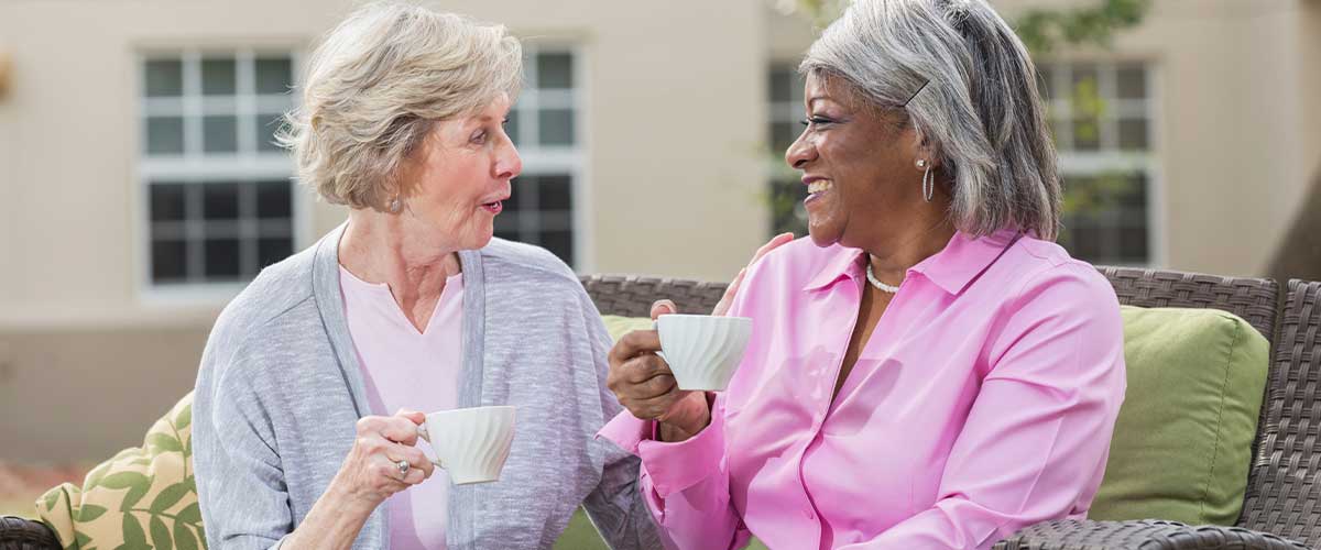 Two senior women enjoying tea together outside
