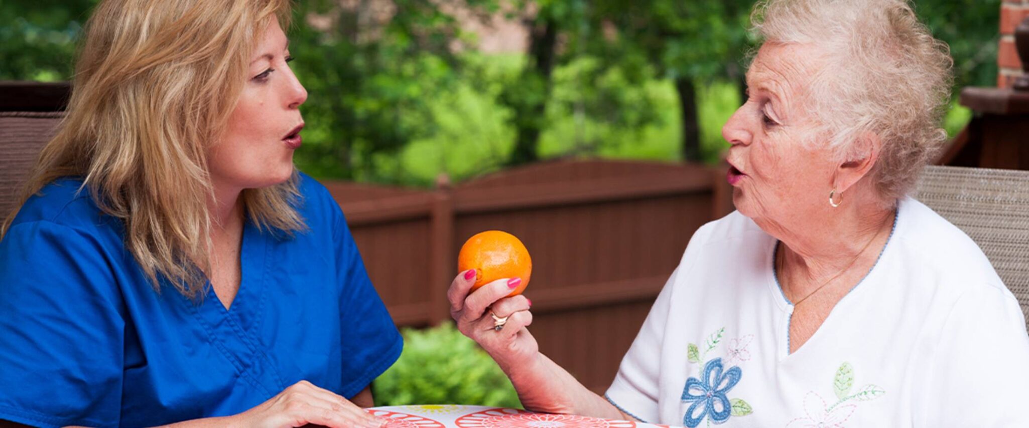 healthcare worker helping a senior pronounce words in speech therapy