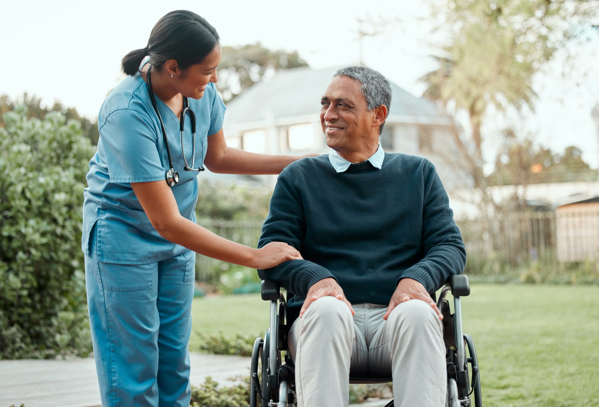Senior man in wheelchair talking to female nurse