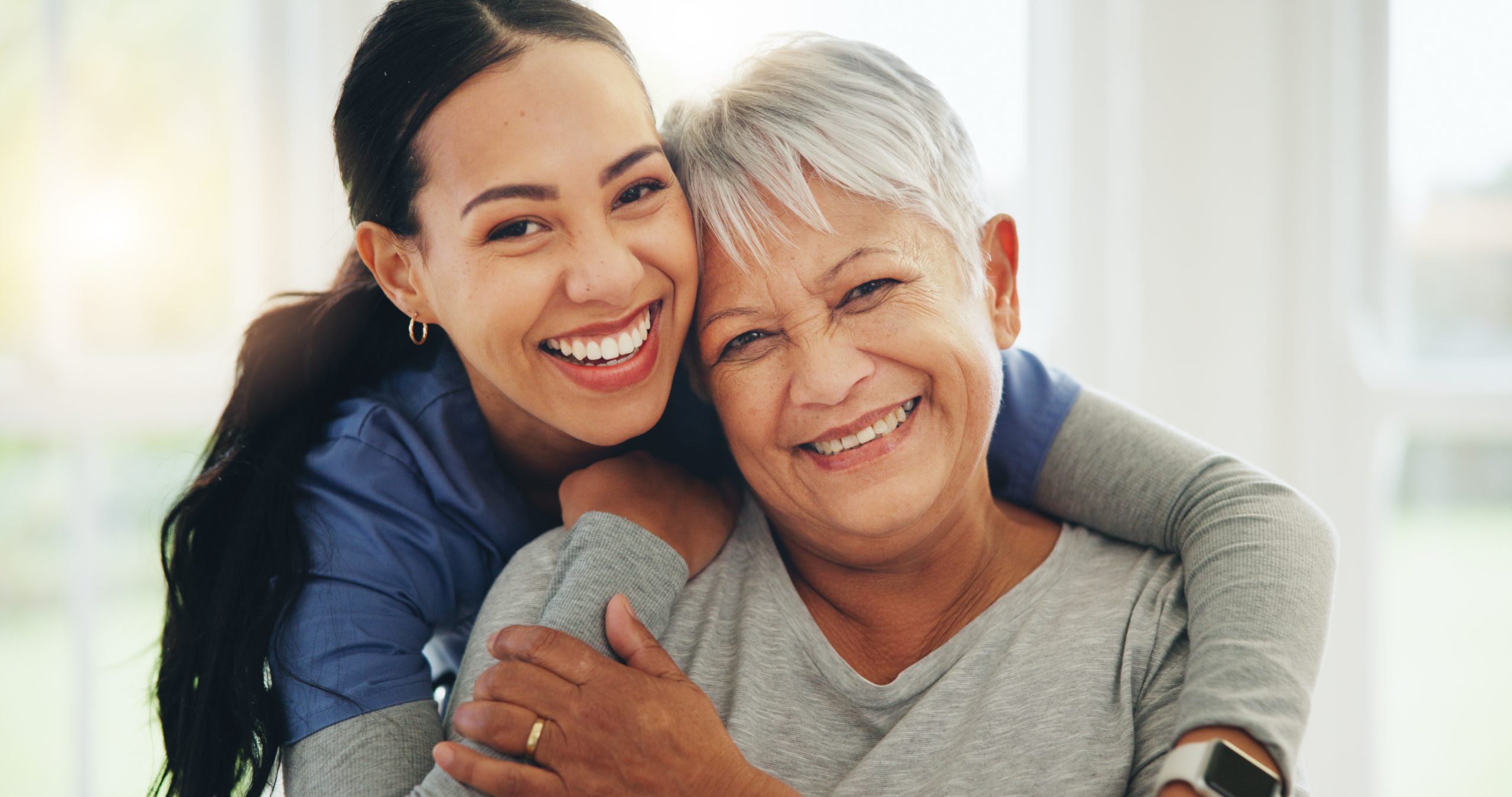 Female nurse hugging senior woman
