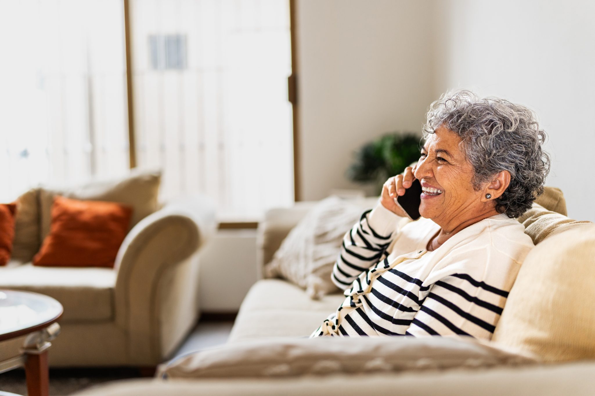 Senior woman talking on mobile phone while sitting on couch