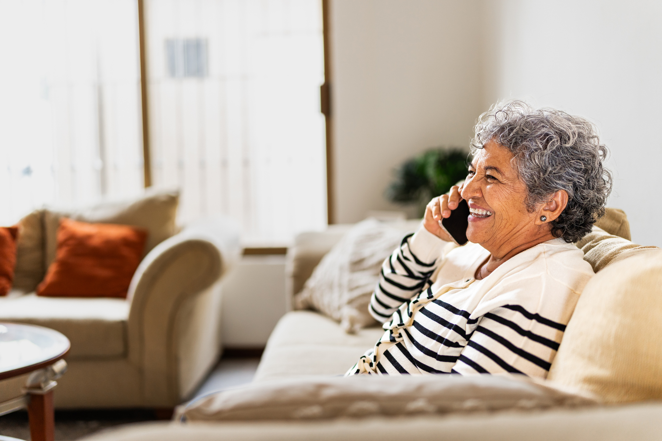 Senior woman talking on mobile phone while sitting on couch